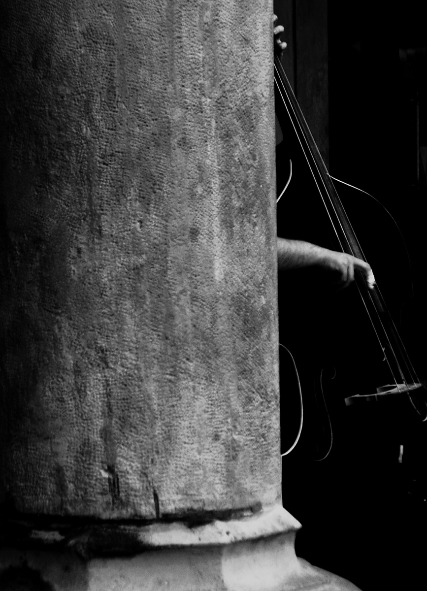 A man playing the double bass partially obscured by a building column