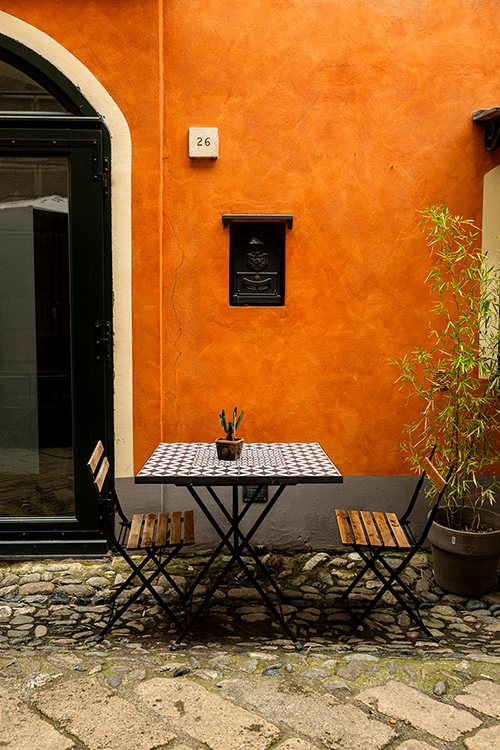 A table with two chairs standing by an orange restaurant wall