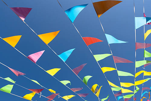 Colorful pennants hanging on strings against a backdrop of blue sky