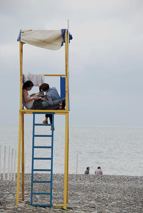 Two girls looking at a magazine on a lifeguard's tower on the beach in Batumi