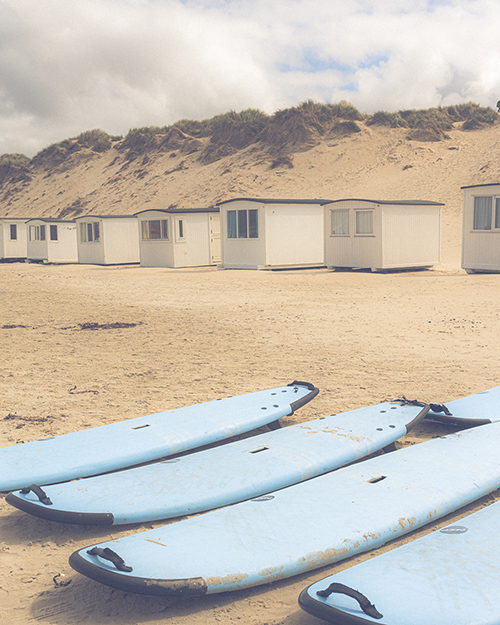 Windsurfing boards lying on the beach in front of beach huts